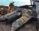Un marin prépare une énorme ancre de bateau, expliquant comment fonctionne une ancre de bateau : elle s'enfonce dans le fond marin pour stabiliser le navire.
