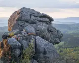 Imponujące góry stołowe o szarej skale, z zielonymi lasami w tle.
