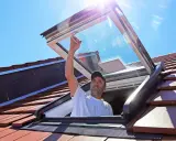 Mann installiert Dachfenster. Informieren Sie sich über Dachfenster Kosten und die Vorteile von mehr Licht.
