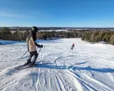 Person åker skidor i Luleå en solig dag. Barn åker skidor i bakgrunden.