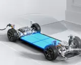 Telaio di un'auto elettrica con un pacco di **batterie al litio per auto elettriche** luminoso e un cavo di ricarica collegato.