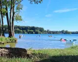 Słoneczny dzień nad jeziorem Pławniowice. Ludzie kąpią się i relaksują na dmuchanych zabawkach.
