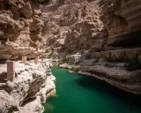 Wadi Shab w Oman: czy warto? Zielona woda w kanionie, skalne ściany i ścieżka z kamiennymi słupkami. Niesamowite widoki.