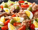 Ein bunter Nizza Salat mit Thunfisch, Ei, Tomaten, Oliven und Sardellen auf knackigem Salatbett.
