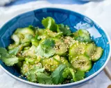 Frischer Gurkensalat mit Sojasauce, Koriander und Sesam in einer blauen Schüssel.