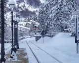 Stazione innevata, binari coperti di neve, lampioni e alberi imbiancati. Un paesaggio da **campo di Giove** in inverno.