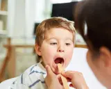 Bambino con bocca aperta durante visita medica per sospetta laringite.