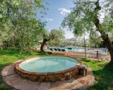 Un angolo di paradiso per dormire in fattoria con bambini: una piccola piscina circondata da ulivi, con una più grande sullo sfondo.