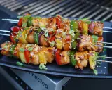 Huli Huli Chicken Spieße mit Paprika, Zwiebeln und Ananas, glasiert und mit Sesam bestreut, auf einem Grill.