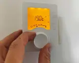 Main tenant ajuste le thermostat pour un mode confort, affichant 19.0°C.