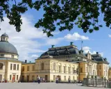Drottningholms slott, där kungen bor, med sin imponerande kupol och gula fasader under en blå himmel med moln.