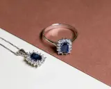 Anello e pendente con un intenso rubino blu al centro, circondato da piccoli diamanti scintillanti.