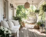Porche pequeño entrada casa con banco, sillón colgante de mimbre y plantas.