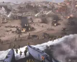 Desant na plażę w Company of Heroes. Żołnierze szturmują brzeg, płoną pojazdy, w tle miasto.