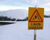 Varning för lavin vid Kebnekaise. Ett gult varningsskylt med en hand, skidor och rep i en röd triangel.
