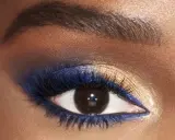 Ojo con un audaz maquillaje de ojos azul y dorado. Delineador azul vibrante y sombras doradas brillantes resaltan la mirada.