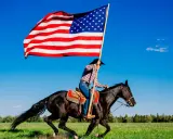 Kowbojka na czarnym koniu niesie flagę USA. To obraz wolności i dzikiego zachodu, pełen ciekawostek o Ameryce.