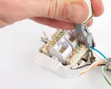 Hand legt Kabel an Netzwerkdose auf. Werkzeug drückt blaue Ader in LSA-Leiste.