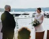 Panna młoda w białej sukni i pan młody w garniturze podczas ceremonii ślub rzymski nad jeziorem.