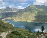 Sentiero facile tra i laghi gemelli alpini, con montagne verdi e un cielo azzurro con nuvole bianche.