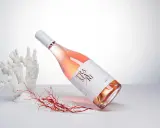 Flasche Roséwein von Cantine San Marzano, umgeben von Korallen und Seetang, auf hellem Hintergrund.