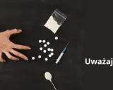 Dwie ręce walczą o kontrolę nad przedmiotami związanymi z narkotykami: strzykawką, tabletkami i proszkiem. Uważaj na fentanyl.