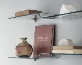 Idee mensole ingresso: vetro curvo con libri antichi, vaso ambrato e scultura in marmo.