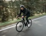 Mężczyzna w kasku i okularach jedzie na rowerze szosowym przez las. To świetny sposób, jak schudnąć na rowerze, poprawiając kondycję.