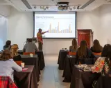 A presenter discusses market performance at Christie's, showing auction data to an audience.