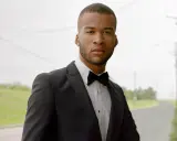 A man in a black tuxedo with a bow tie, ready for black tie weddings.