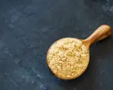Cuillère en bois remplie de poudre de maca, évoquant ses nombreux bienfaits pour la santé et l'énergie.