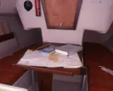 Vue du premier 22 intérieur d'un voilier, avec une carte marine, des livres et un compas.