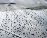 Krople wody na ciemnym lakierze po nałożeniu ceramiki. Efekt perlenia świadczy o hydrofobowości powłoki.