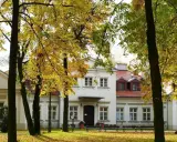 Jesienny spacer wokół dworu Zbożenna. Złote liście drzew otulają zabytkowy budynek.