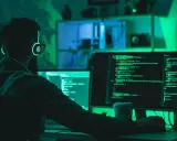 Programista w słuchawkach z podświetleniem pracuje nad kodem na dwóch monitorach. To jego kolejny przypadek testowy.