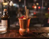 Cocktail in rame, decorato con frutti rossi e cannella, perfetto per un aperitivo Milano Marittima.