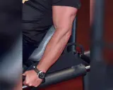 Mann trainiert unterarme im gym. Sein Bizeps ist gut sichtbar, während er sich auf ein Gerät stützt.