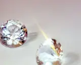Due pietre preziose scintillanti, una sfaccettata e luminosa, l'altra più sfocata, illustrano la differenza tra brillanti e diamanti.