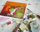 Płótno z barwnym obrazem, tubki farb olejnych Winsor & Newton, paleta i pędzle – idealne narzędzia, by dowiedzieć się, jakimi farbami malować na płótnie.