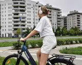 Dziewczyna w słuchawkach na rowerze, słuchając muzyki, przemierza miejską ścieżkę rowerową.