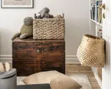 Cesti di vimini per idee arredare con stile: un cesto intrecciato sopra un baule antico, un altro appeso alla porta.