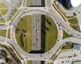 Widok z lotu ptaka na skrzyżowanie z ruchem okrężnym. Samochody i autobusy poruszają się po drogach, a znaki drogowe wskazują, kto ma pierwszeństwo na skrzyżowaniu.