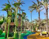 Parque el Palmeral con juegos infantiles coloridos y palmeras altas bajo un cielo azul.