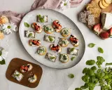 Vackra midsommar-snittar med ost, jordgubbar och örter på en stor tallrik. Perfekt för sommarfesten!