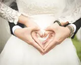 Manos formando un corazón sobre el vestido de novia, símbolo de una boda de platino.