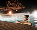 Entspannter Abend in den Thermen NRW. Eine Frau genießt das warme Wasser, umgeben von stimmungsvoller Beleuchtung und Dampf.
