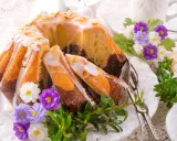Pyszne ciasto na wielkanoc, marmurkowe, polane lukrem i posypane płatkami migdałów, ozdobione wiosennymi kwiatami.