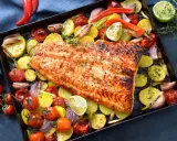 Pescado al horno con patatas, cebolla y tomate, asado a la perfección con hierbas frescas y un toque de limón.