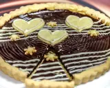Una deliziosa crostata al cioccolato, decorata con cuori e fiorellini di pasta frolla, pronta per essere gustata.