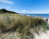 Strandgras und Strandkörbe am Meer. Ein ruhiger Ostsee Geheimtipp mit blauem Himmel und sanften Wellen.